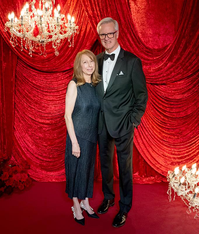 Centre Stage Gala guests posing at the photo backdrop featuring dramatic red velvet curtains and crystal chandeliers at the COC fundraiser event